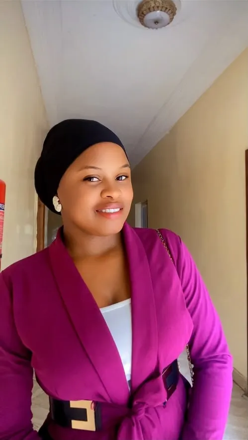 Rita smiling, wearing a black head wrap and a magenta jacket
