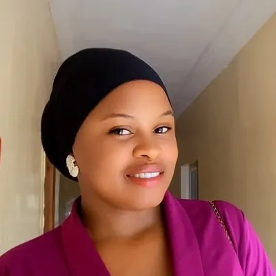 Portrait of Rita in a black head wrap and magenta jacket