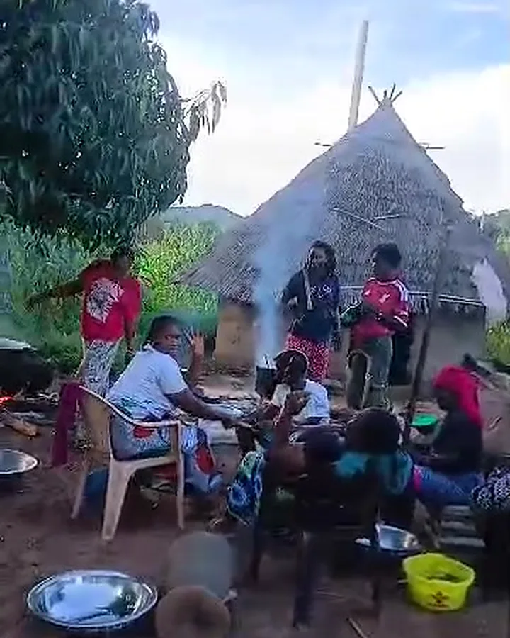 Women cooking together in front of thatched huts in the village